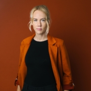 Sorority Obfrau Katja Grafl, Porträtfoto in orangefarbenen Blazer und schwarzem Top vor orangefarbenen Hintergrund